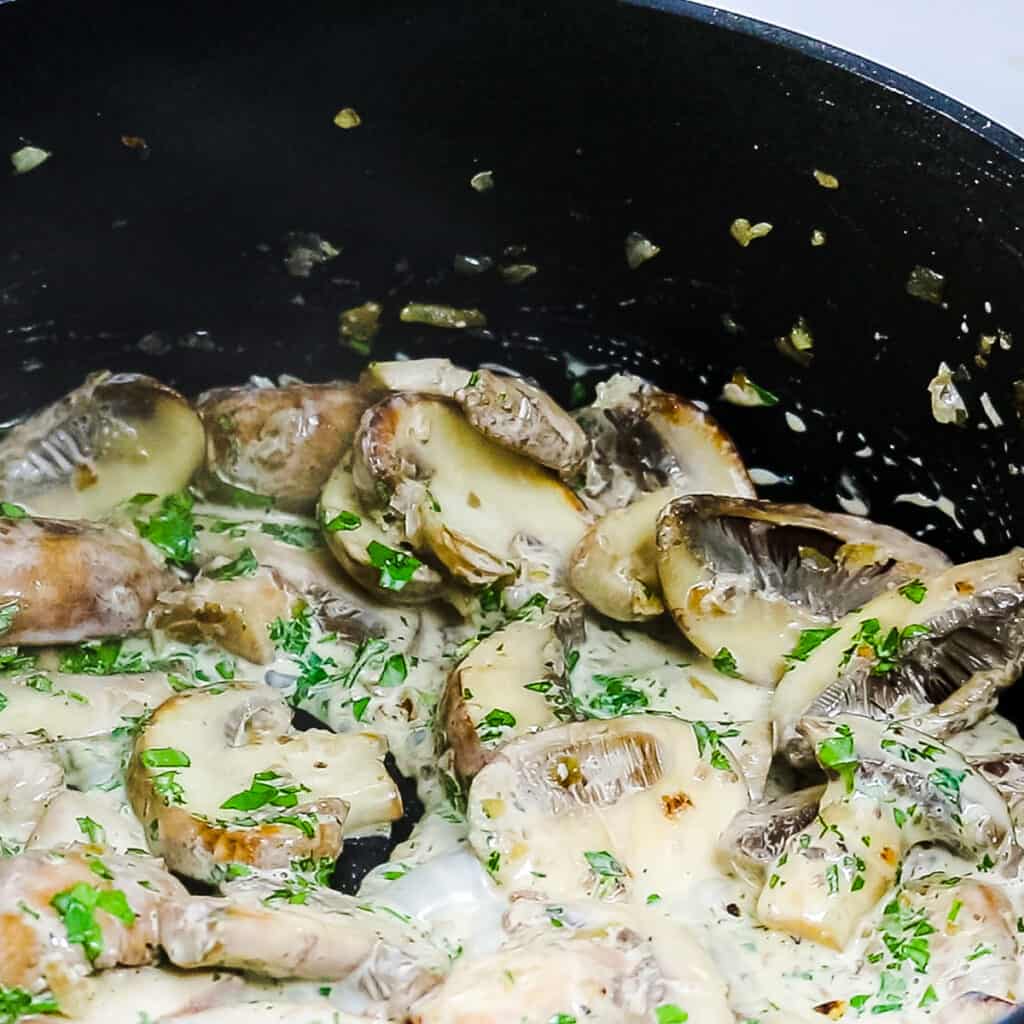 A pan with mushrooms in a bubbling cream sauce