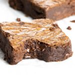 Easy Chocolate Brownies scattered on baking paper with the front one bitten