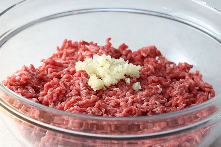 Mince garlic with ground beef in a mixing bowl