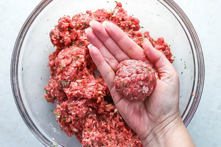 A fully formed meatball in an open hand