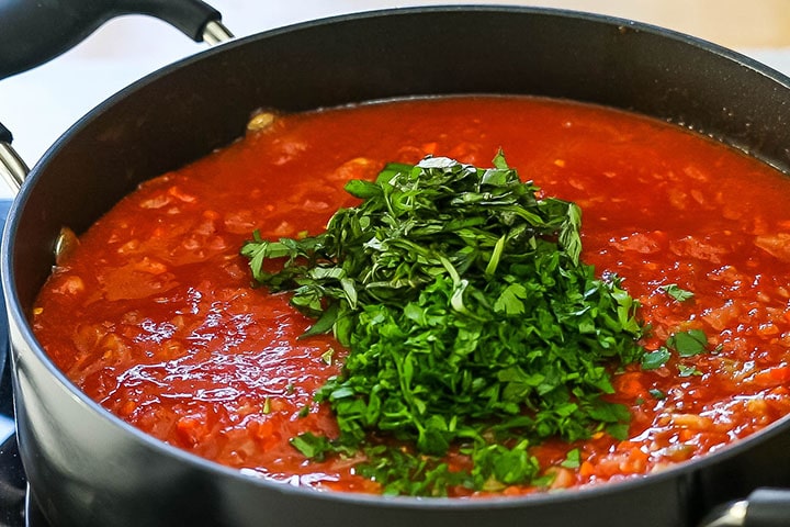 The herbs and tomatoes added to the pan with the vegetables