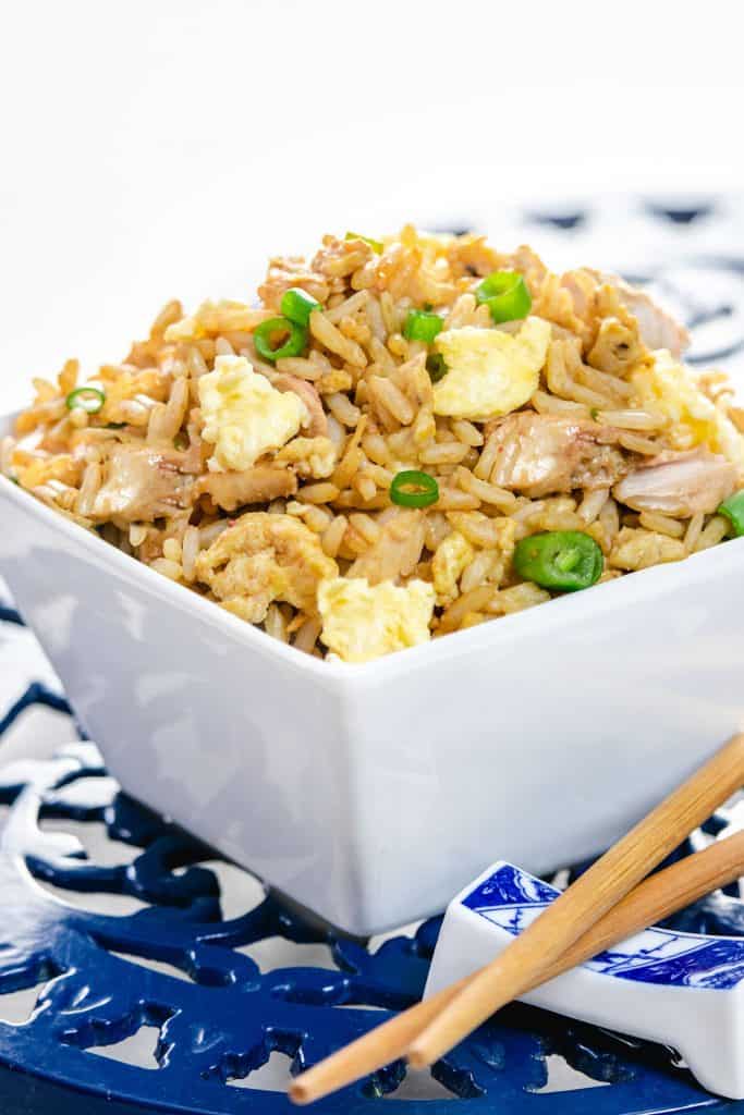 A bowl of fried rice with chop sticks next to it