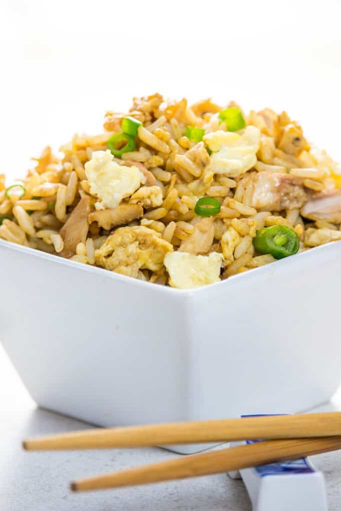 A close up of a bowl of fried rice with chop sticks next to it