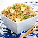 A close up of a bowl of fried rice with chop sticks next to it