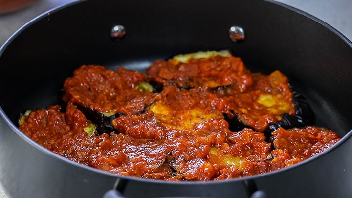 The eggplant slices in the pan covered with tomato sauce