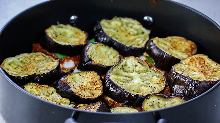 A second layer of eggplant added to the pan with the first layer