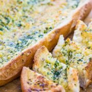 Perfect Garlic Bread sliced on a cutting board with a bread knife next to it