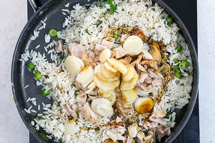 water chestnuts and chicken added to the rice in the pan