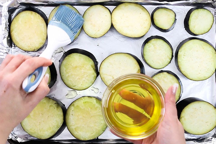 Eggplant slices being brushed with olive oil