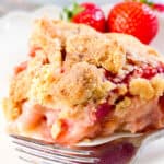a slice of Strawberry Rhubarb Pie with a fork and stawberries on the plate