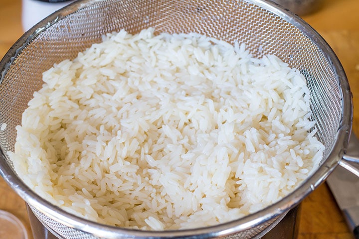 cooked white rice in a collander.