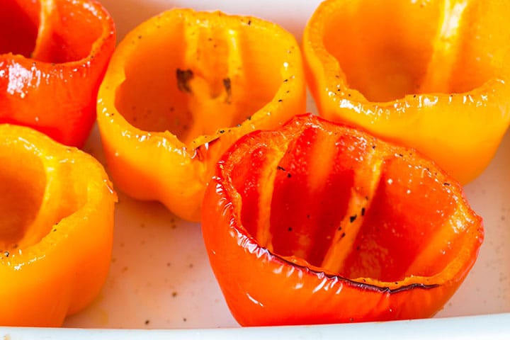 The roasted coared peppers in the roasting pan