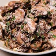 a bowl piled high with creamy garlic mushrooms sprinckled with parsley
