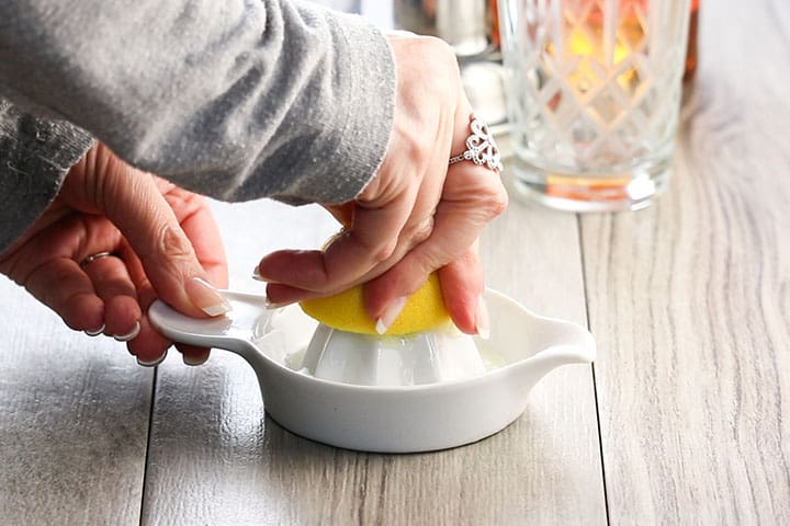 Lemon being pressed into a juicer.
