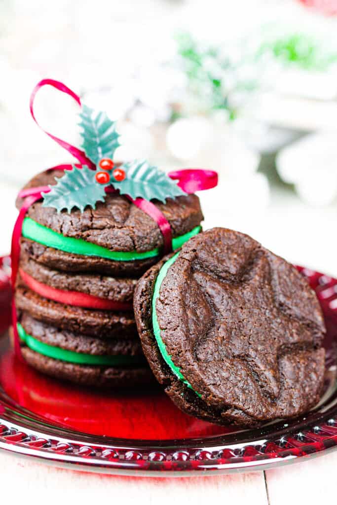 Christmas Oreo Cookies wraped with ribbon and holly on a red plate