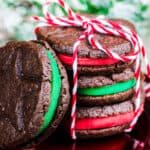 A stack of Christmas Oreo Cookies wrapped with a bowwith one leaning against them