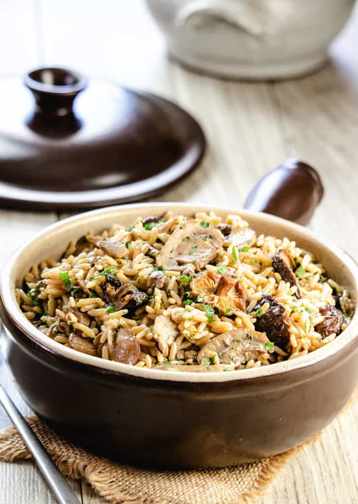 easy mushroom rice pilaf in a serving dish with the lid behind it