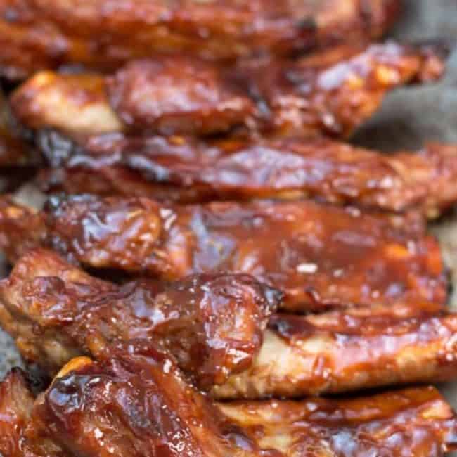 Barbecued sticky glazed ribs on a pan with sauce brushed over then