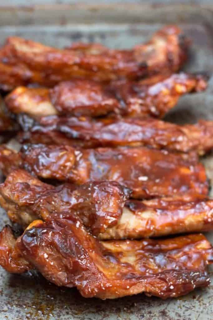 Barbecued sticky glazed ribs on a pan with sauce brushed over then