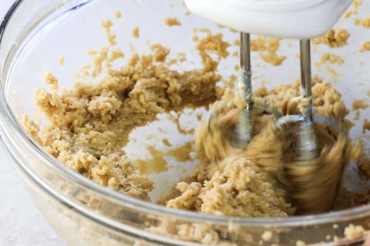 Butter and sugar being beaten together in a glass bowl