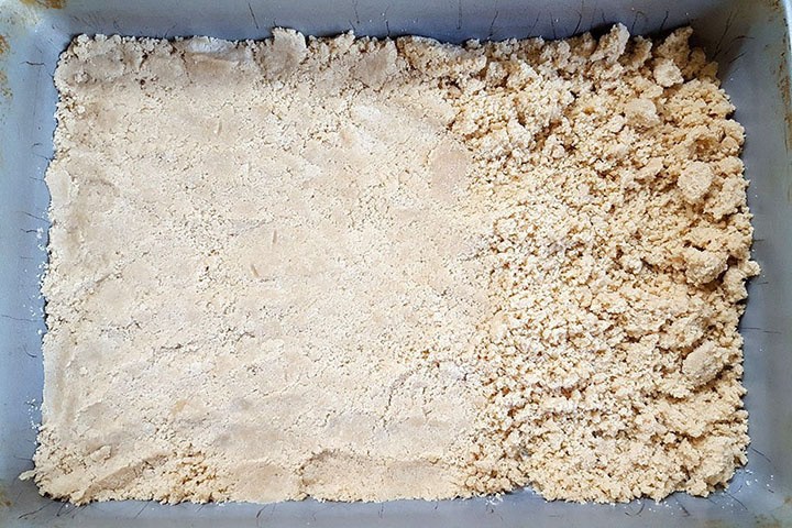 The base mixture being pressed into the pan