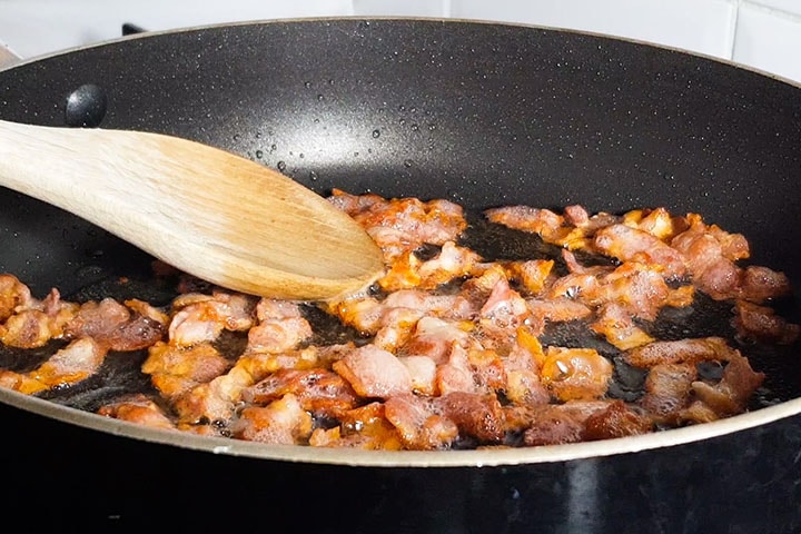 chopped bacon cooking in a pan