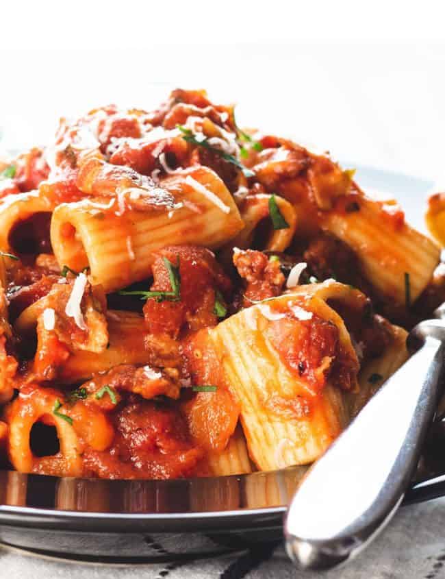 A heaping bowl of pasta with Amatriciana Sauce topped with grated cheese