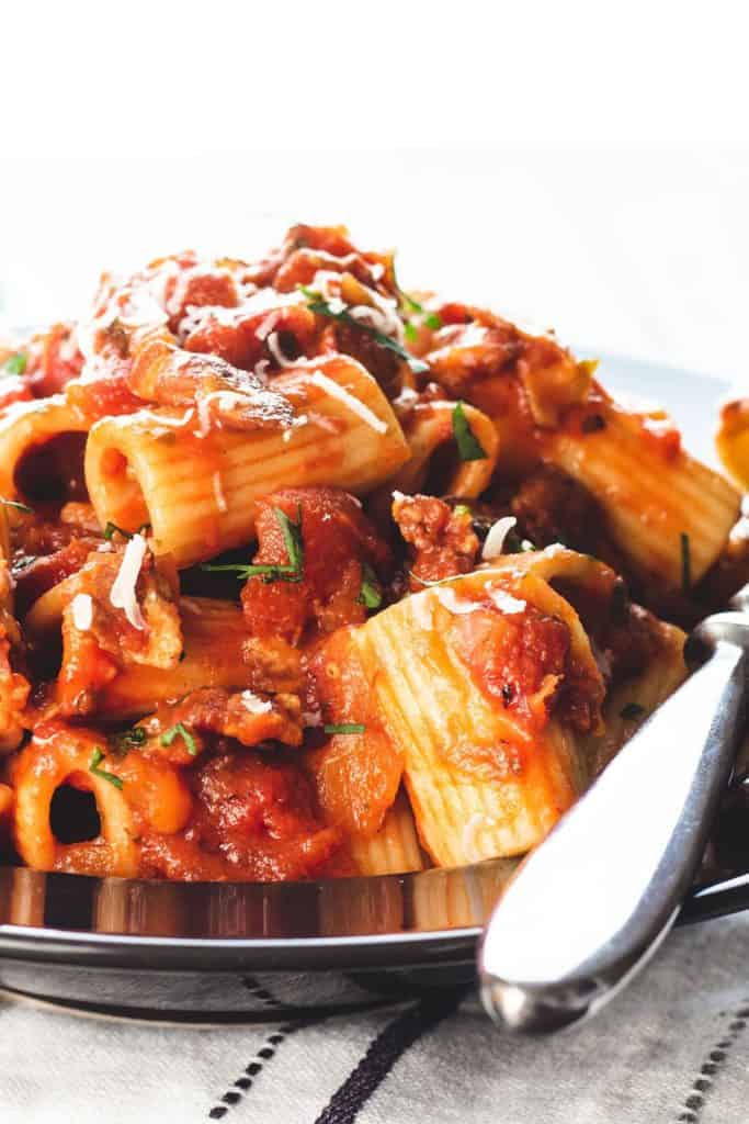 A heaping bowl of pasta with Amatriciana Sauce topped with grated cheese
