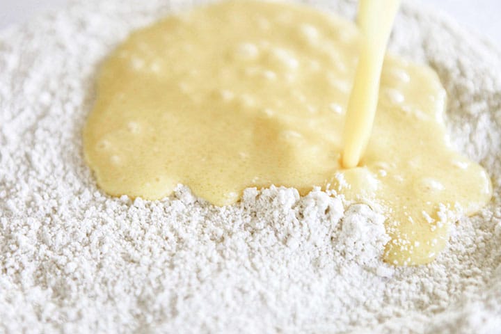 The egg mixture being poured into the flour mixture