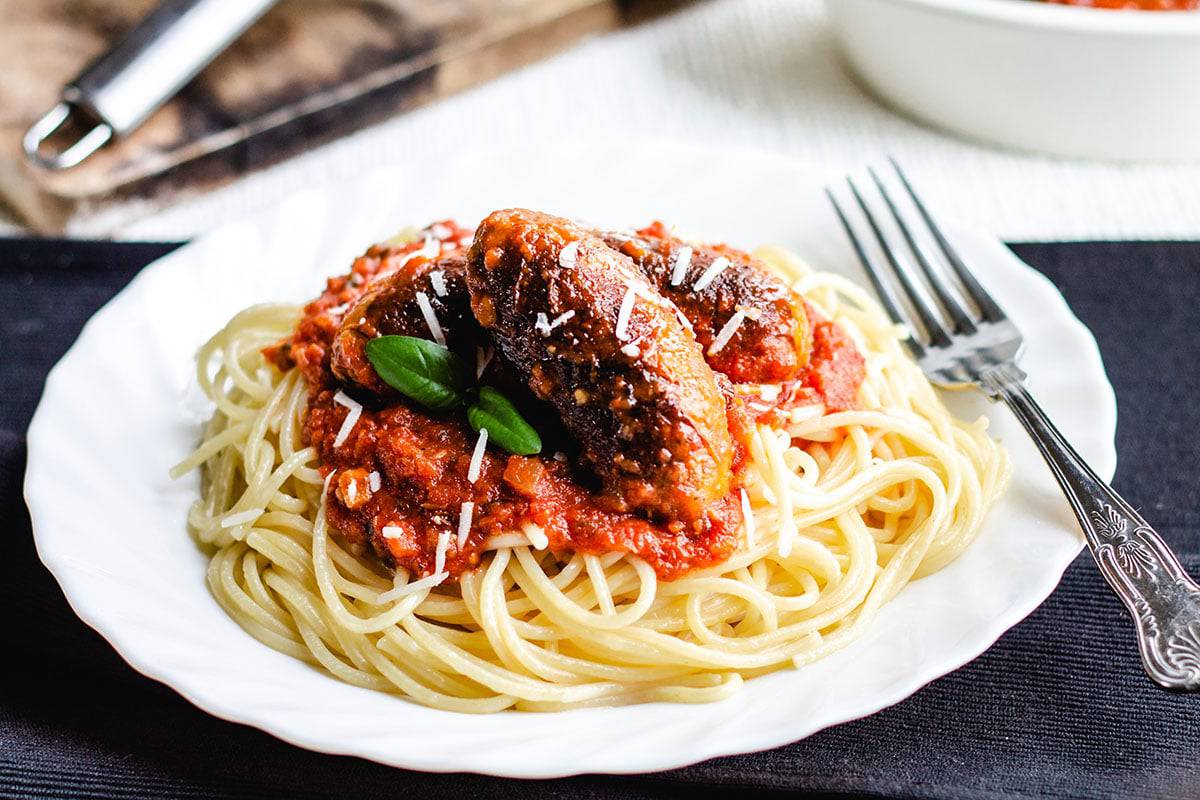 Spaghetti and Italian Sausage with a block of cheese and grater in the background