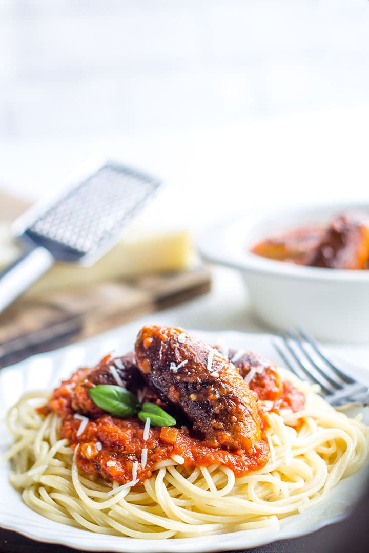 Spaghetti and Italian Sausage with a block of cheese and grater in the background