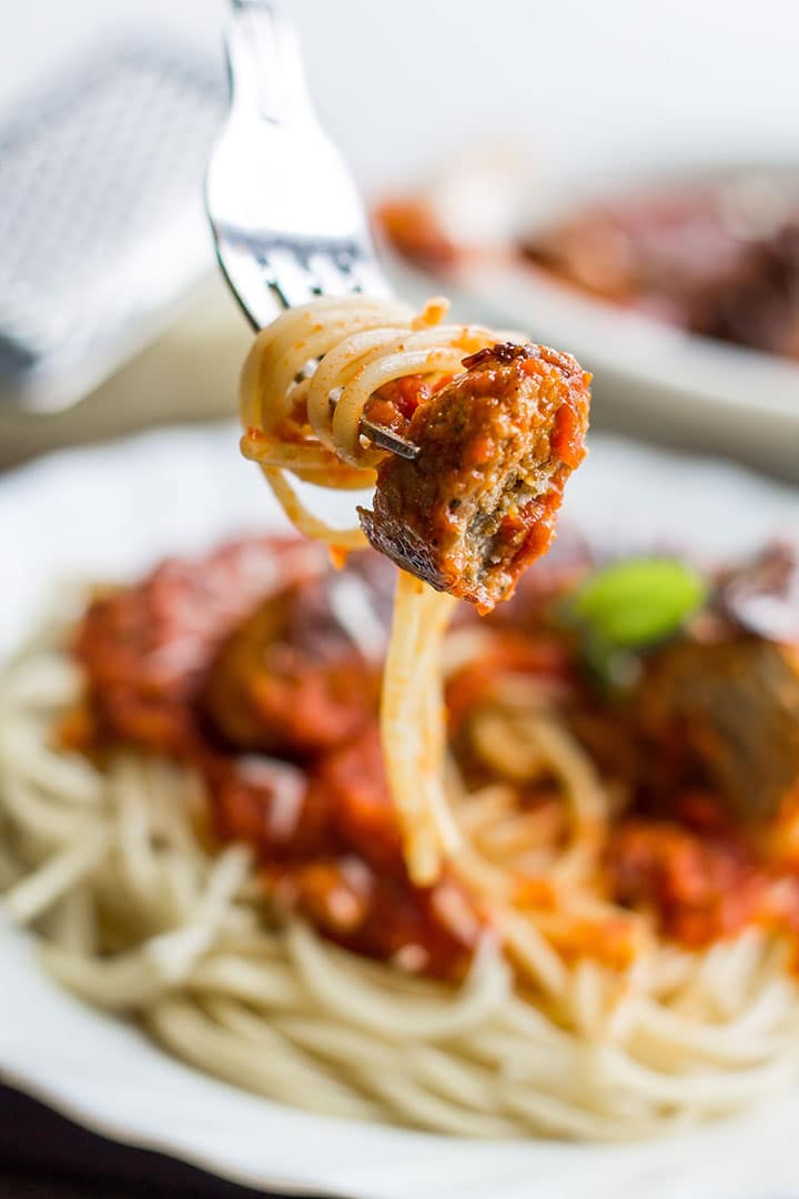 a fork with twirled spaghetti and a slice of sausage on it