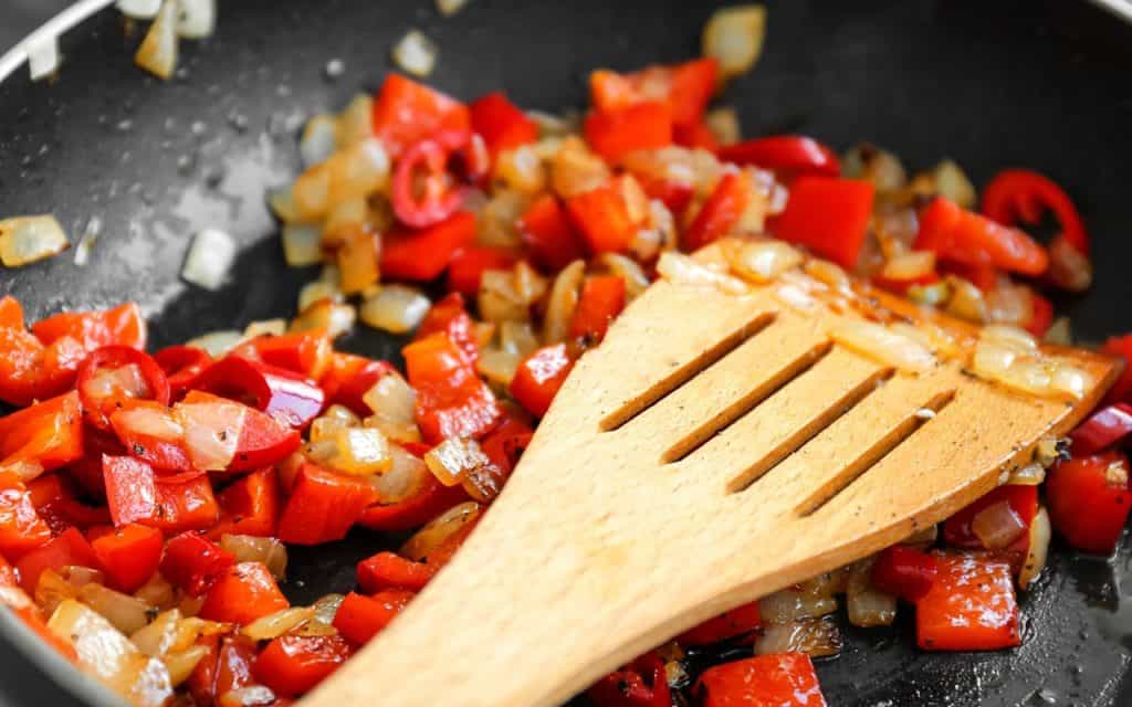 peppers and onions cooking together in a pan