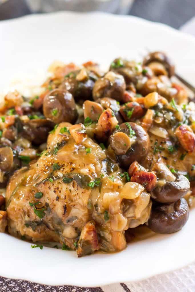 A close up of a plate of Chicken, Mushrooms, and Sauce on a white plate