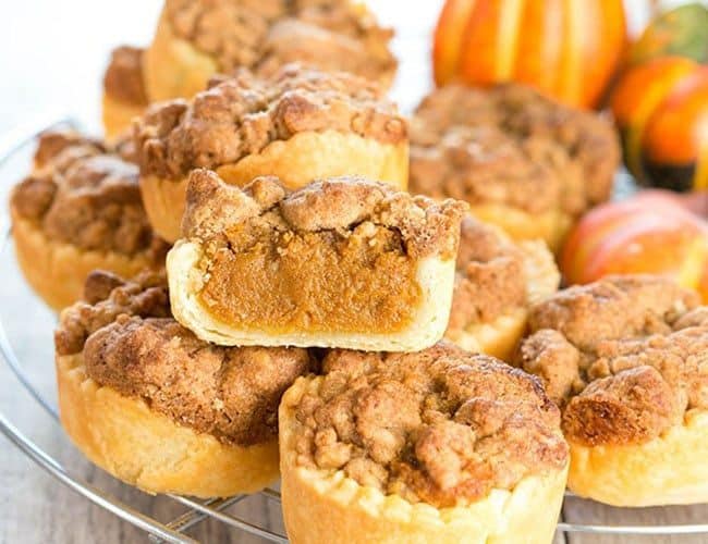 Pumpkin Streusel Tarts stacked on a cooling rack with one cut open to show the filling