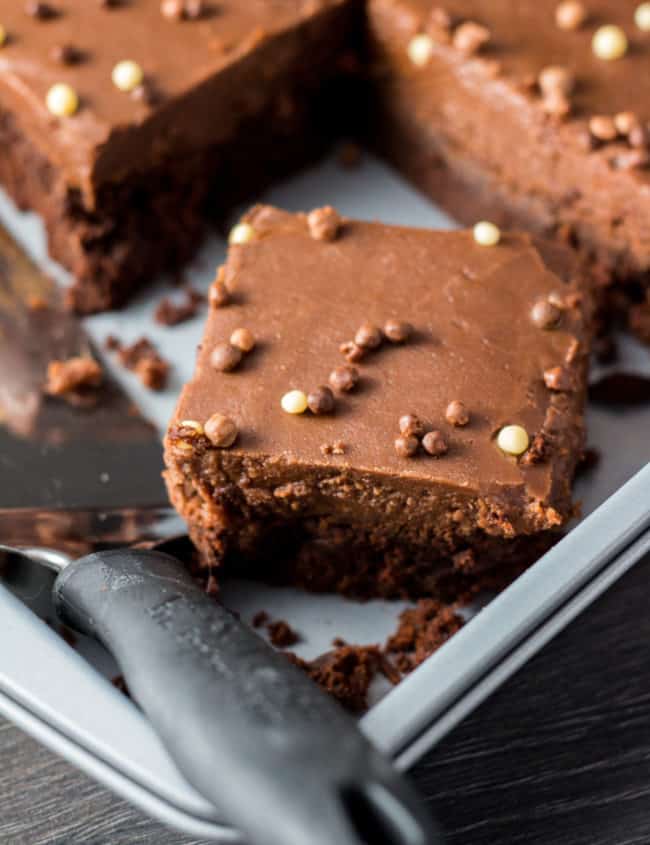 a chocolate fudge sheet cake with a slice cut out of it