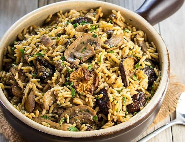 easy mushroom rice pilaf in a serving dish with the lid behind it