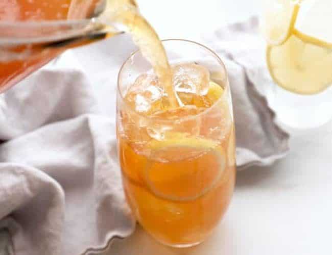 Pouring sweet lemon iced tea over lots of ice and lemon slices