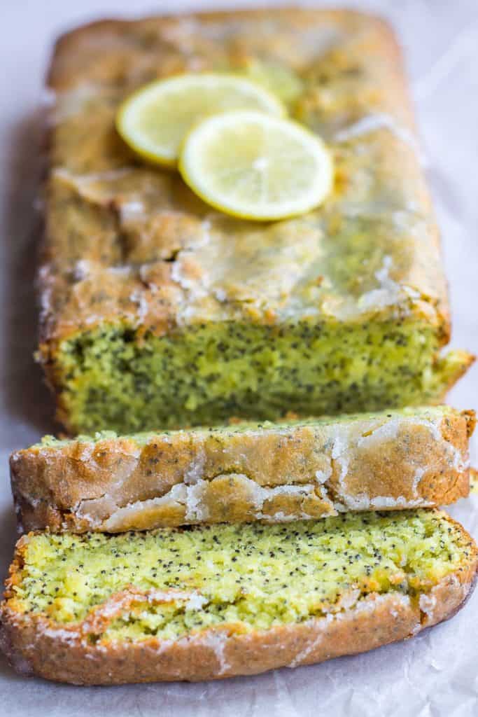 Lemon Drizzle Cake with three slices cut out of it and lemons on top