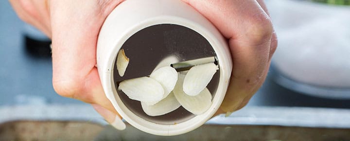 garlic being sliced through the garlic slicer