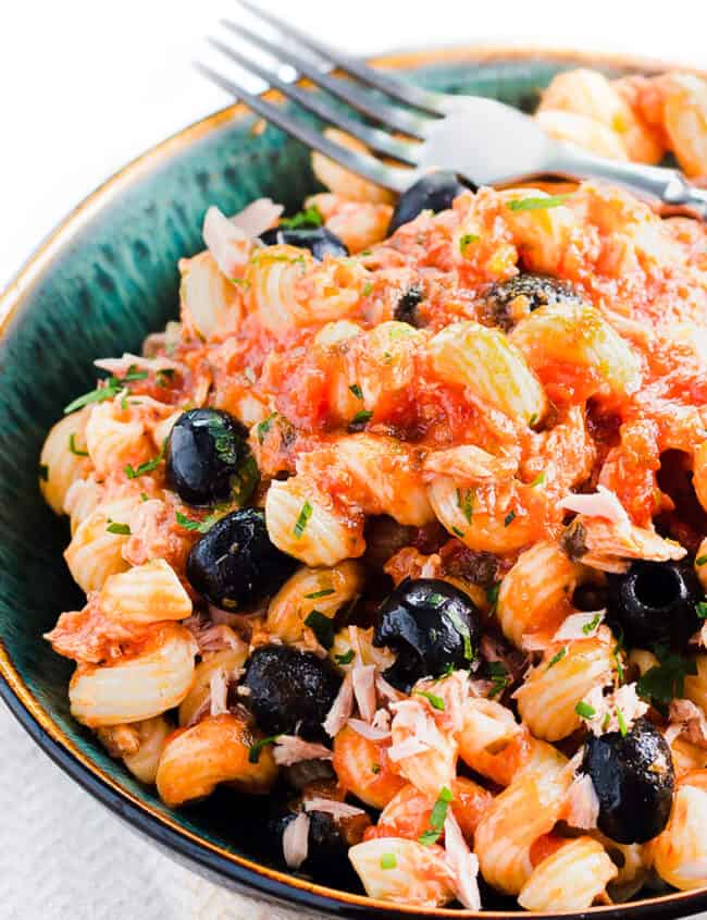 A plate of tuna pasta with olives and tomato sauce