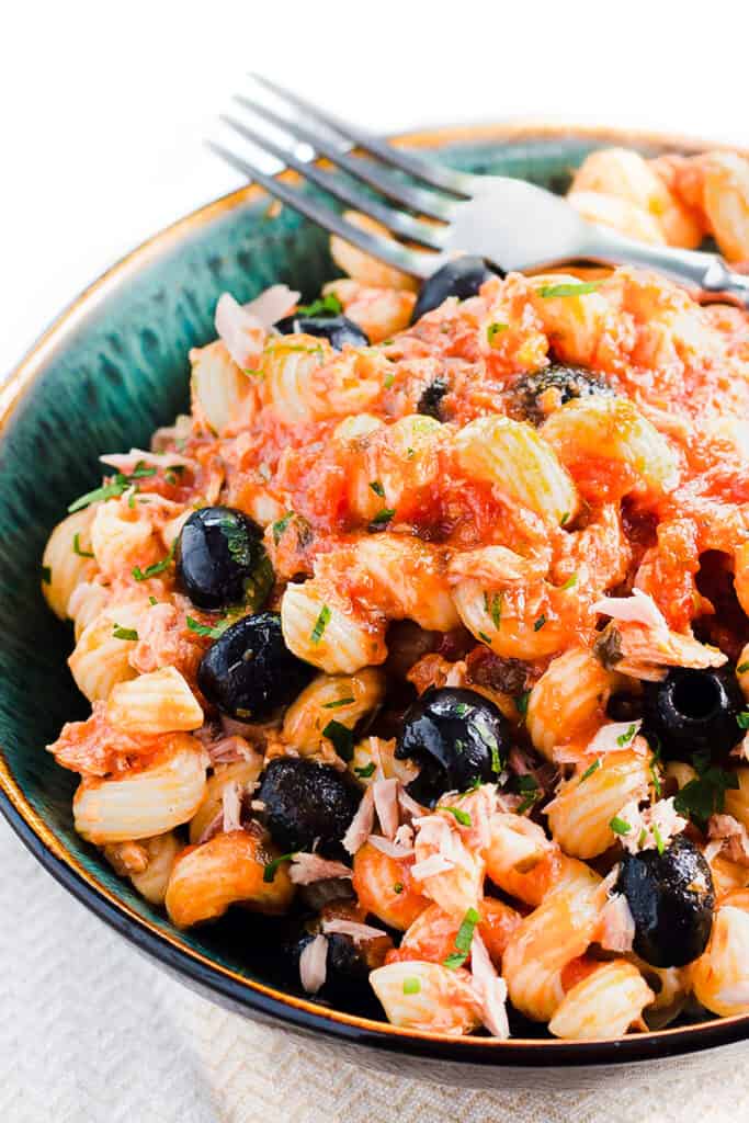 A plate of tuna pasta with olives and tomato sauce