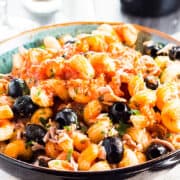 A plate of tuna pasta with olives and tomato sauce