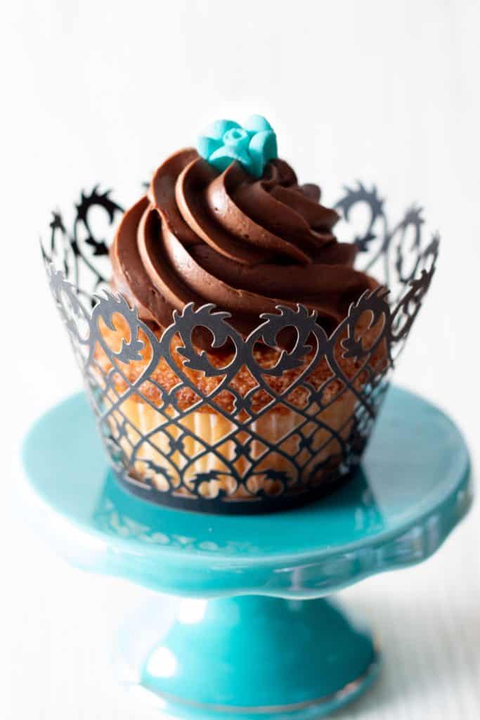 a cupcake swirled with chocolate frosting topped with a little blue rose