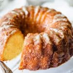 An orange Bundt cake on a glass cake stand.