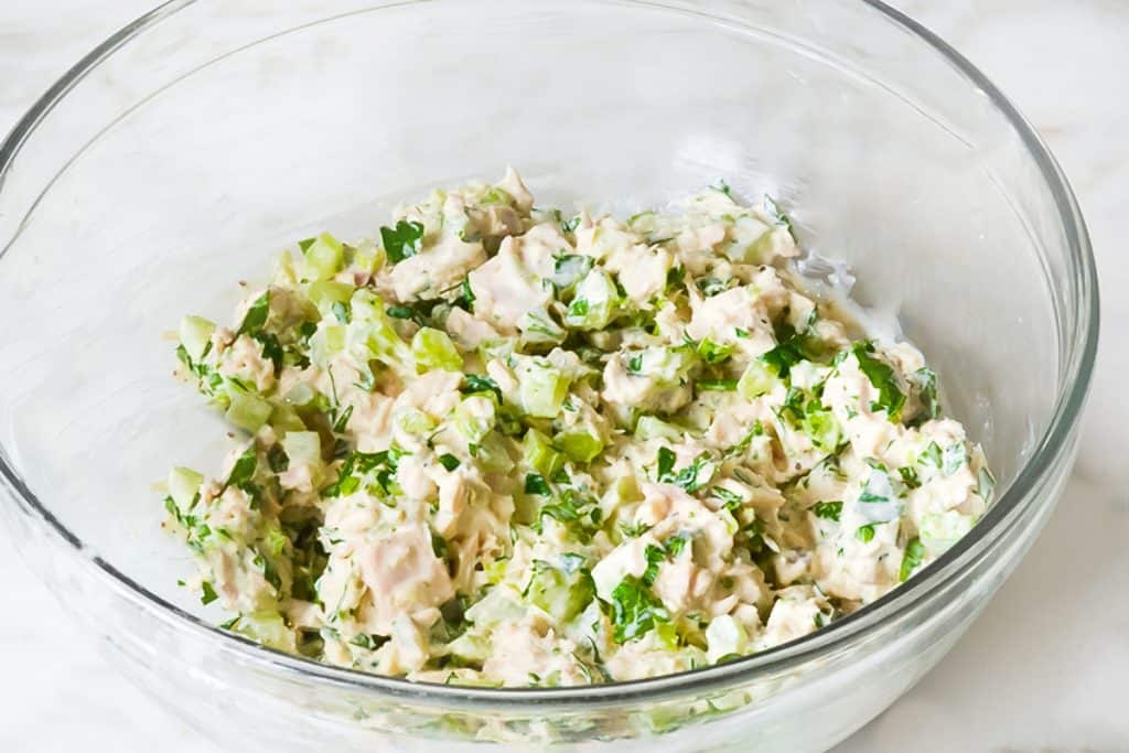 the ingredients for the tuna salad mixed together in a glass bowl