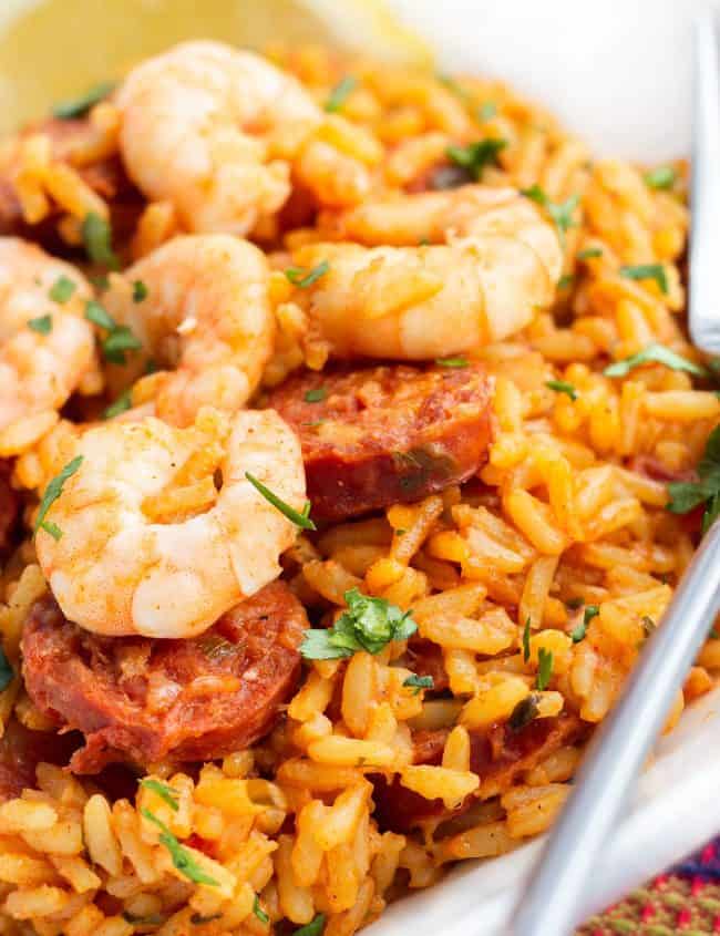 A dish of yellow rice topped with sausage and shrimp