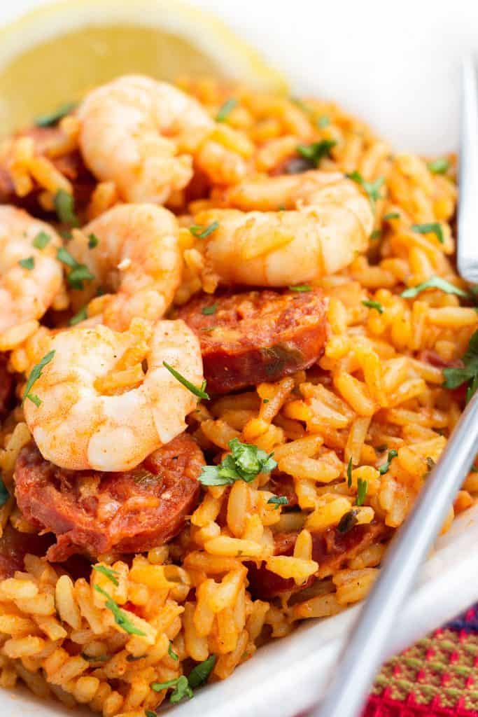 A dish of yellow rice topped with sausage and shrimp