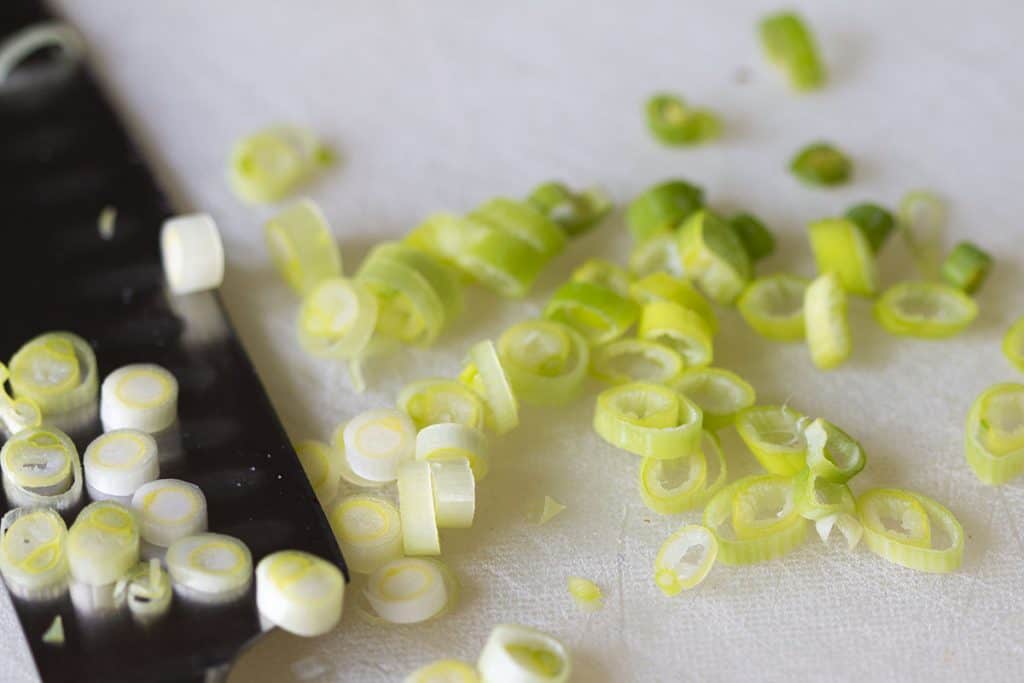 sliced green onions on a cutting board with a knife