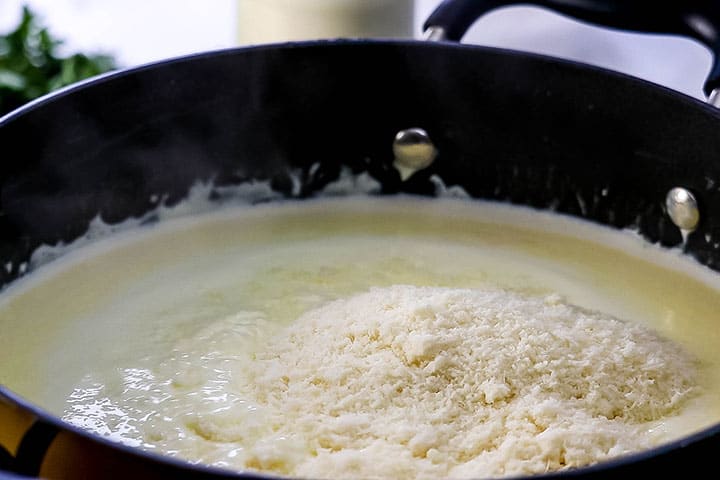 The cheese being added to the sauce in the pan